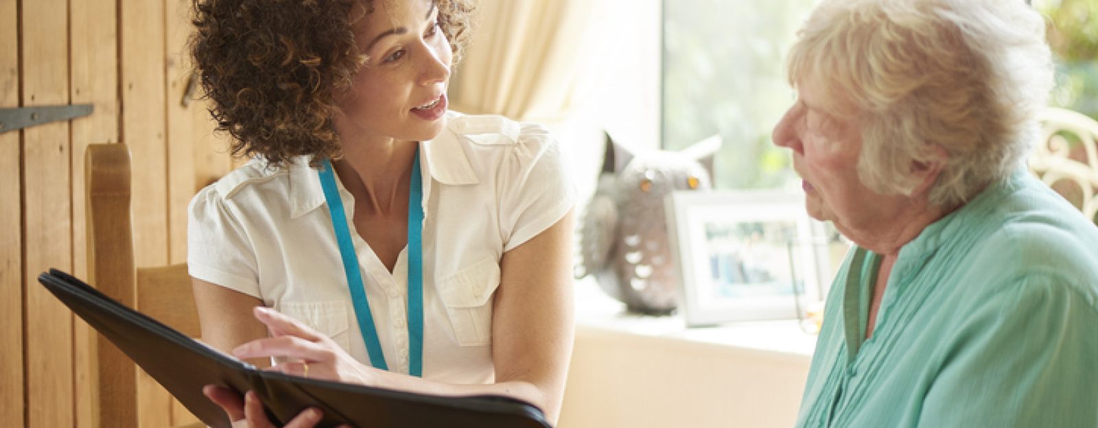 a health navigator chatting to a senior client at her home. She is discussing the senior woman’s options on her digital tablet.