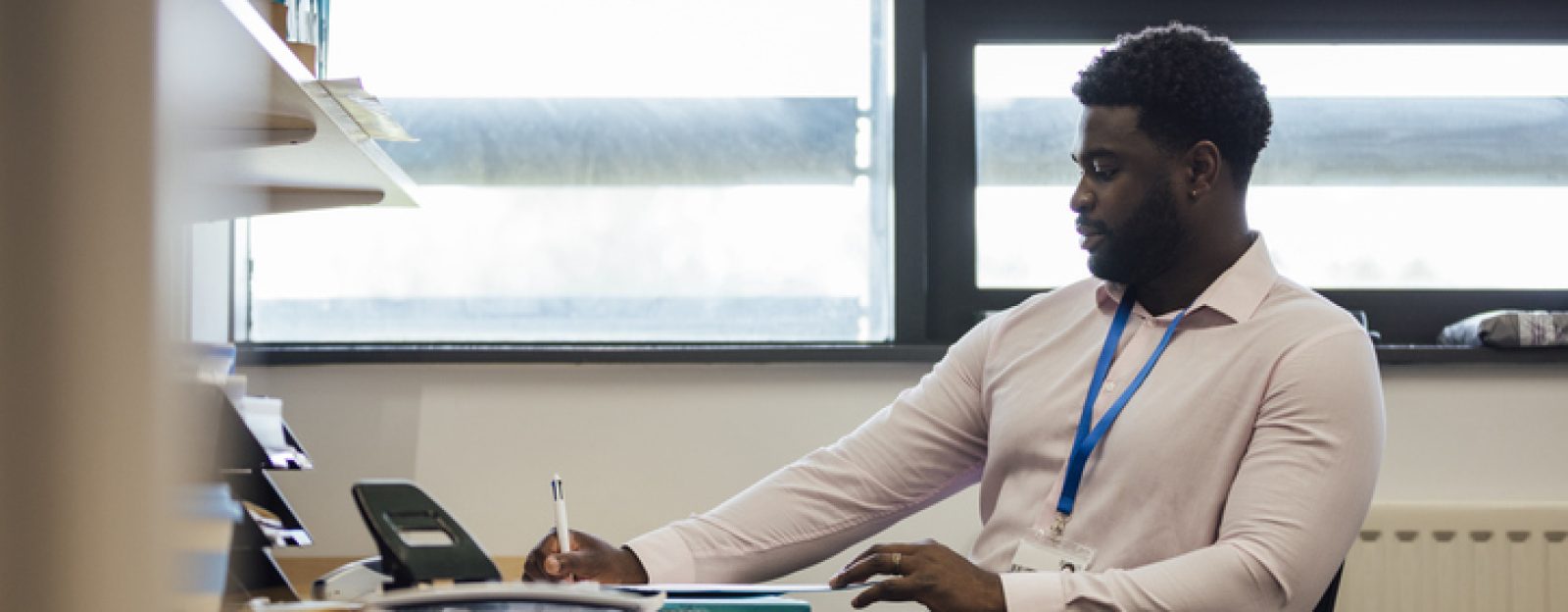 A leisure duty manager writing while sat at a desk.
