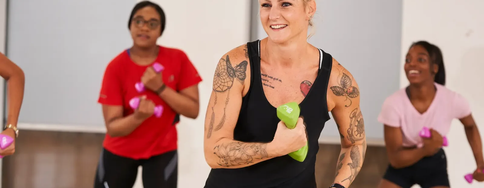Group exercise instructor with dumbbells teaching group of women.