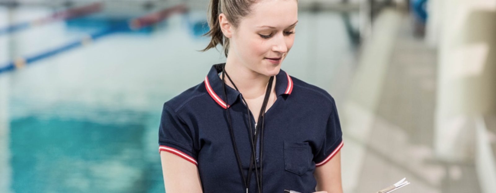 a swim coordinator writing on clipboard at the pool