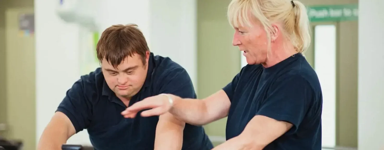 A gym instructor working with a client on using gym equipment