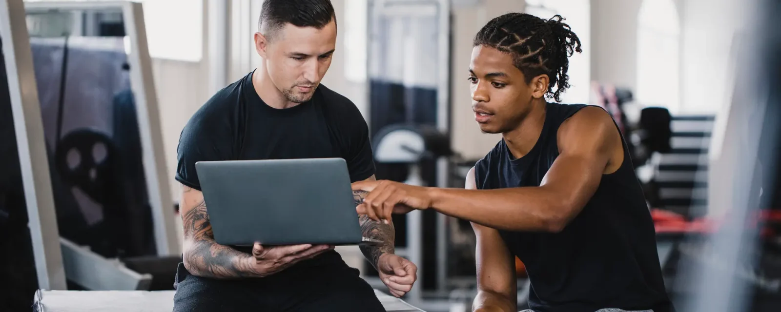 Personal trainer and a client sitting in a gym discussing the clients fitness progress.