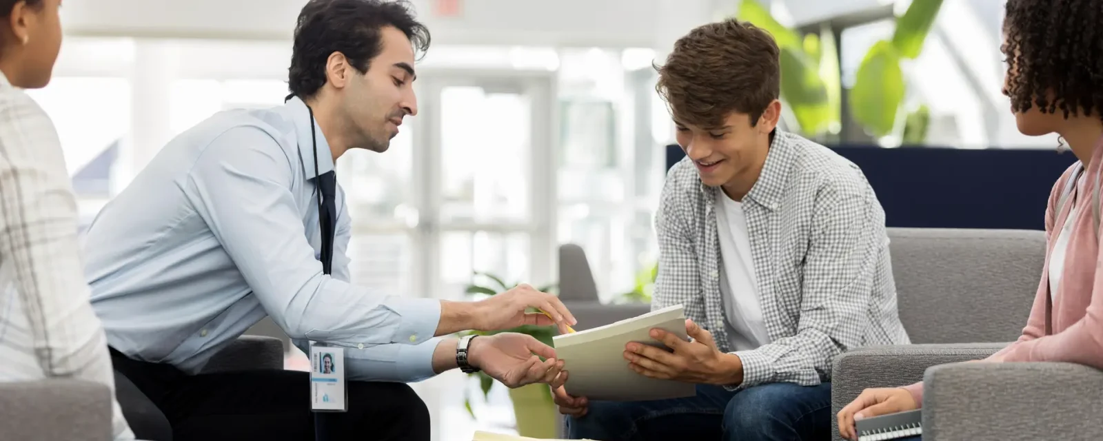 A teacher supporting a group of teenage students with their assignments