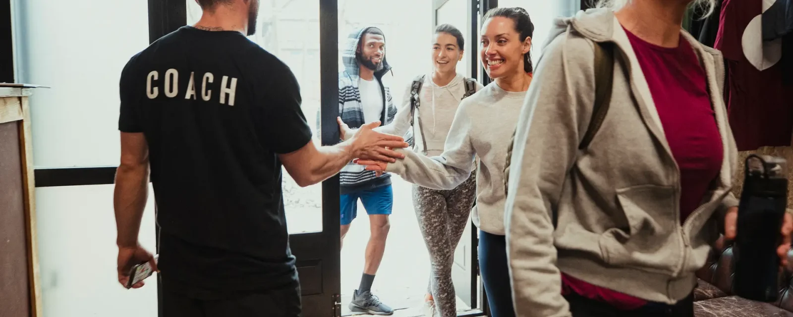 Arriving for an Exercise Class A group of clients entering a gym and saying hi to their coach.