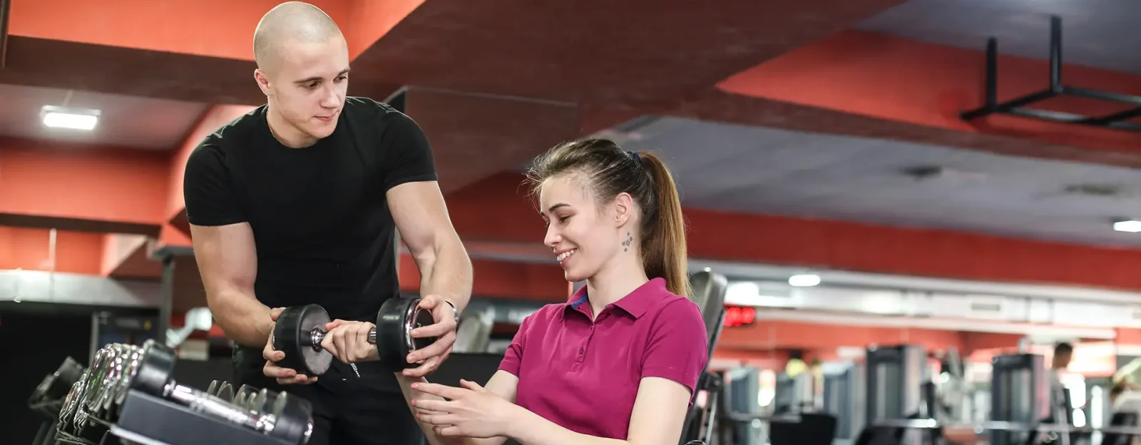 Disabled young woman exercising in a gym with help of her coach